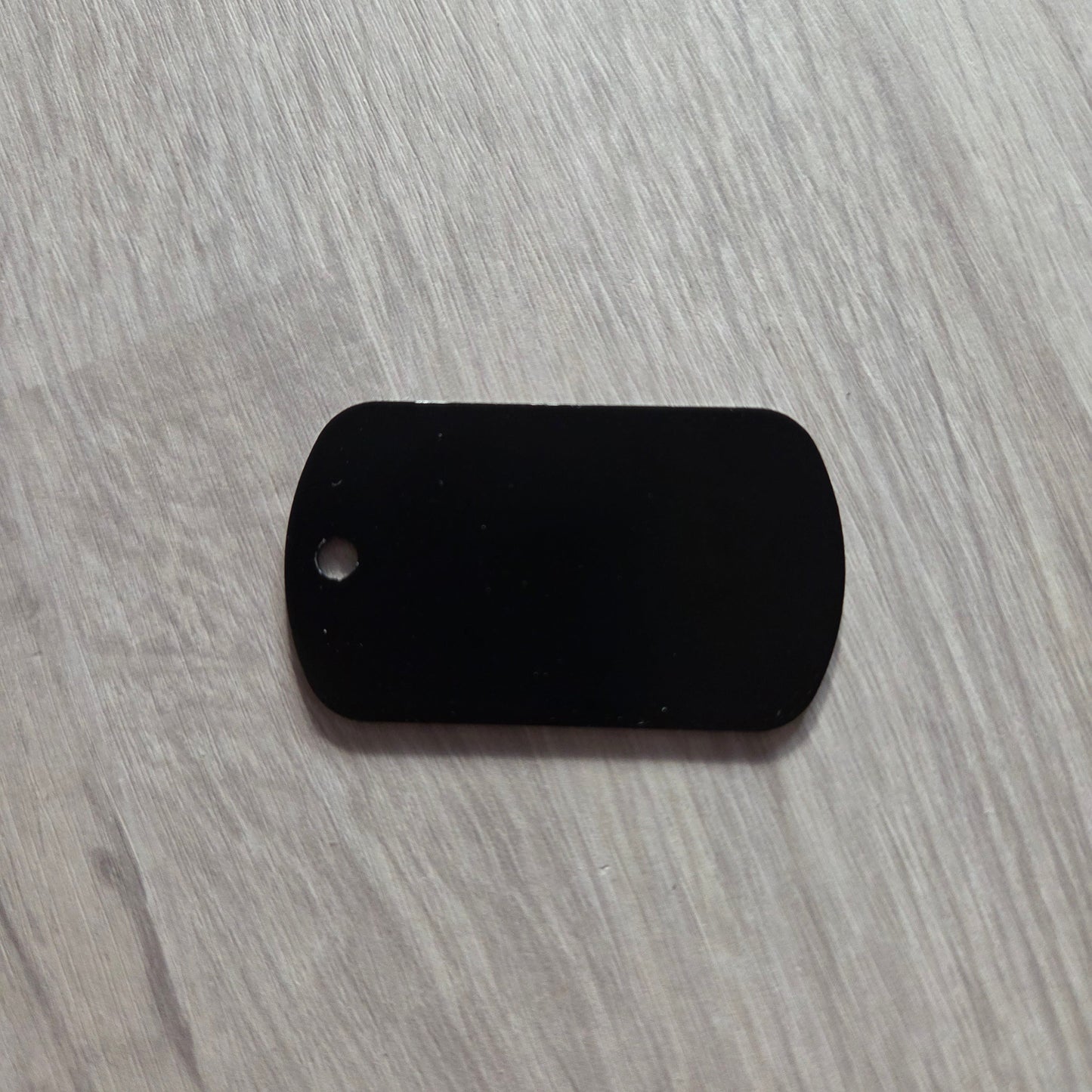 Black dog tag on a gray textured surface
