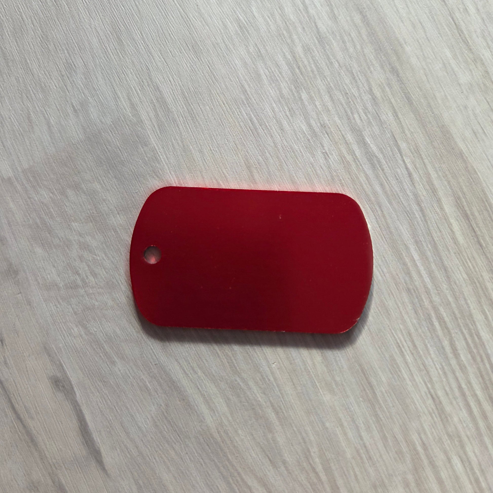 Red rectangular tag with a hole on a light wooden surface