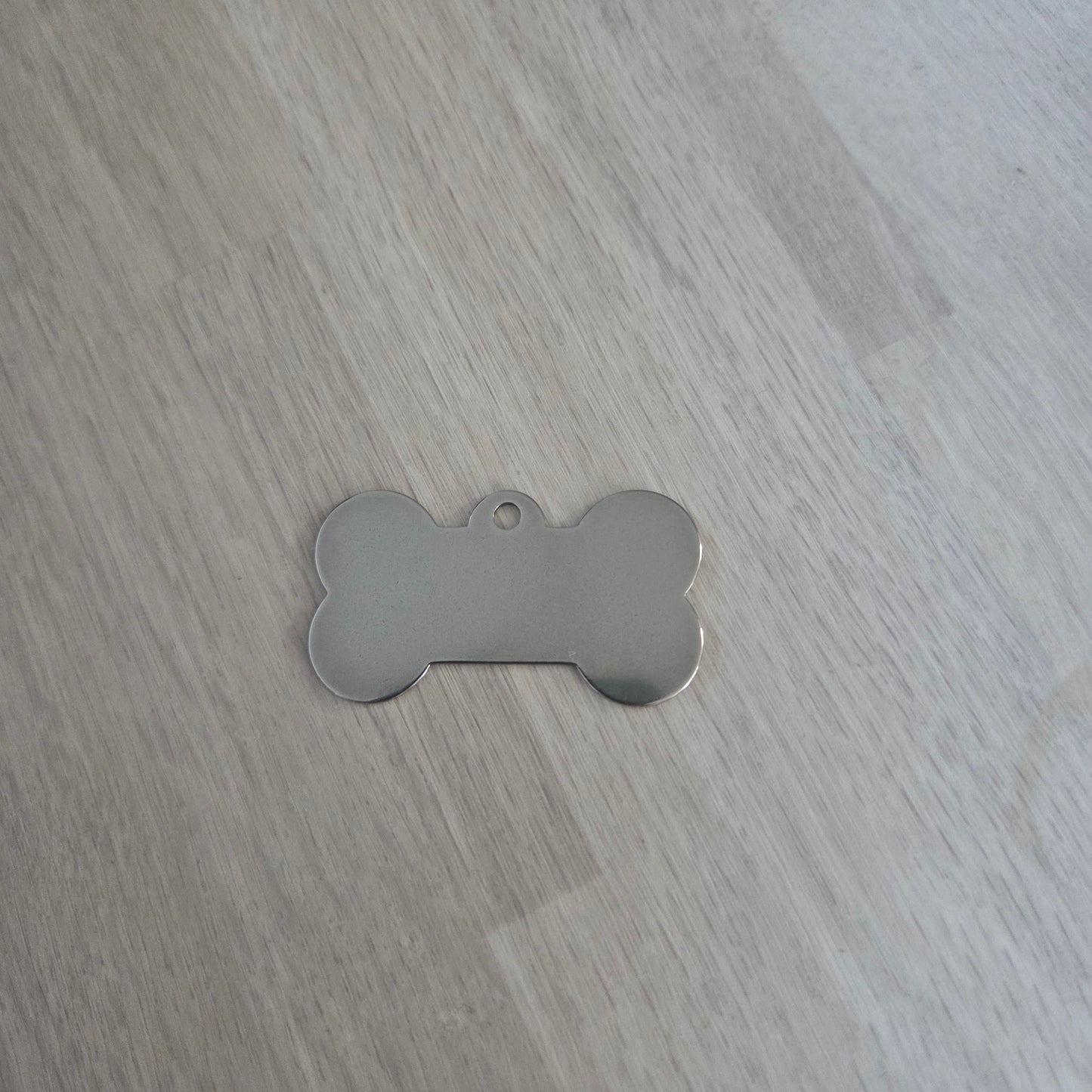 Metallic bone-shaped tag on a wooden surface