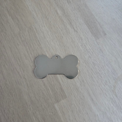 Metallic bone-shaped tag on a wooden surface