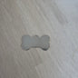 Metallic bone-shaped tag on a wooden surface